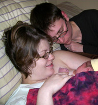 Moms cuddling in bed with their new baby